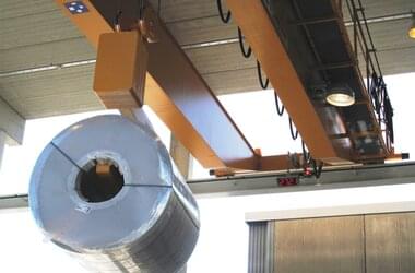 ABUS-kran transporterar rostfria stålrör i en halvöppen hall i Finland