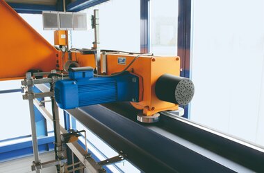 Bilden visar en åkverksbalk med drivet hjul på en kranbana. Längst fram är nedre styrhjul monterade. I åkverksbalken finns en gummistötdämpare.