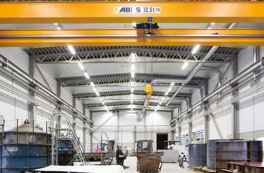 Modern industrihall med ABUS-kran (12,5 ton) och lyftkrokar för effektiv materialtransport i produktionsområdet.