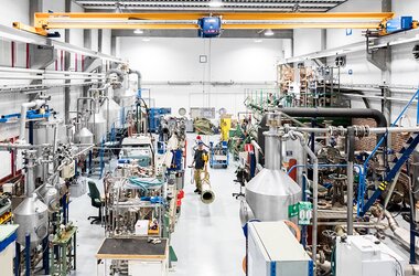 Modern produktionshall med industriella maskiner och en ABUS-krananläggning för exakt materialhantering.